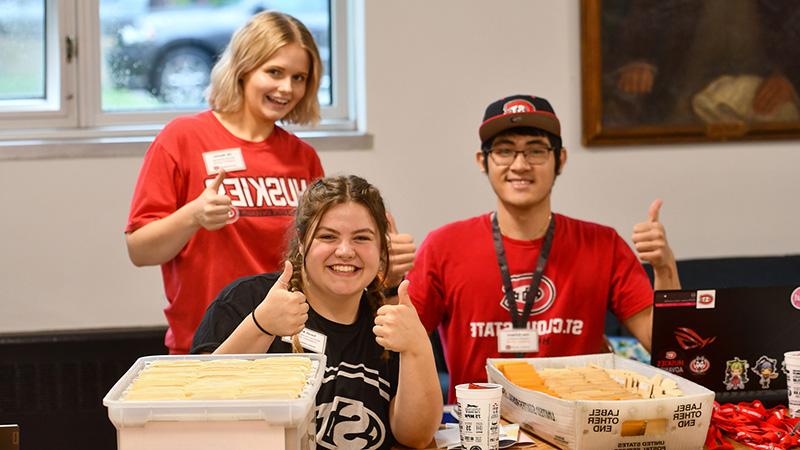 Three St. Cloud State students working a table at an event. 